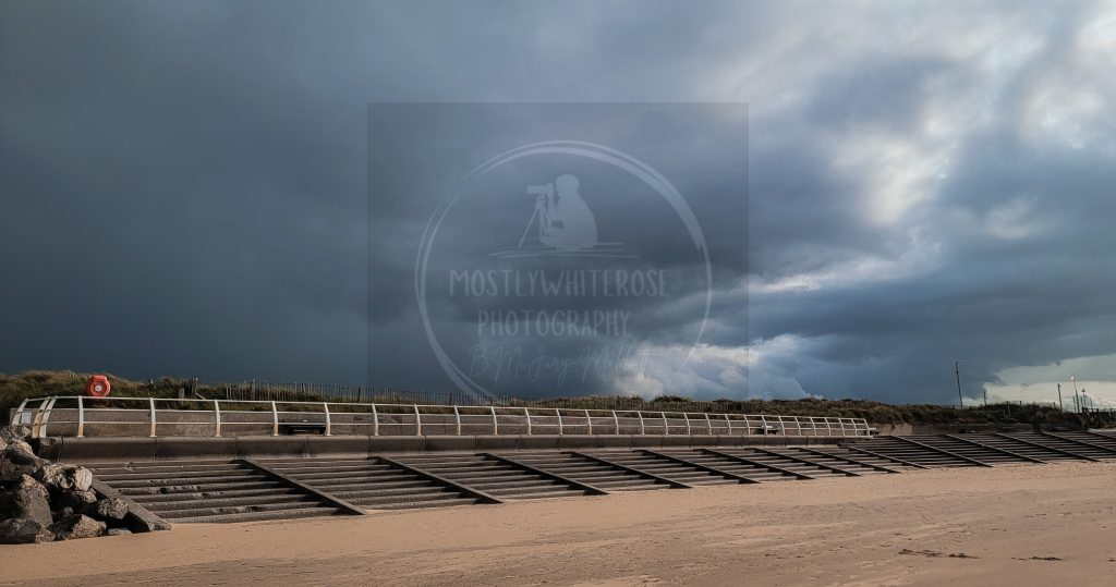 ominous storm dark black angry clouds beach steps bouey rocks